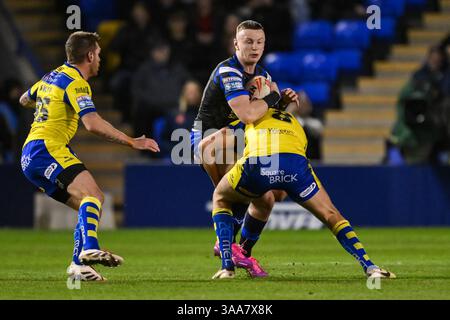 WARRINGTON, INGHILTERRA - 28 MARZO 2025: Ash Handley dei Leeds Rhinos viene affrontato da James Harrison dei Warrington Wolves durante la Betfred Super League Ro Foto Stock