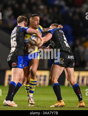 WARRINGTON, INGHILTERRA - 28 MARZO 2025: Paul Vaughan dei Warrington Wolves viene affrontato da Morgan Gannon e Mikolaj Oledzki dei Leeds Rhinos durante la puntata Foto Stock