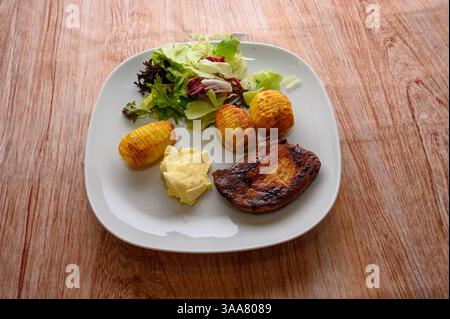 Un pasto ben organizzato presenta un pezzo di carne alla griglia accanto a patate arrosto dorate condite con spezie Foto Stock