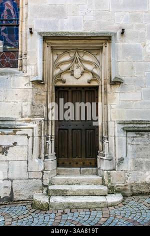Una grande porta in legno con un telaio in pietra. La porta è aperta e i gradini che vi conducono sono in pietra Foto Stock