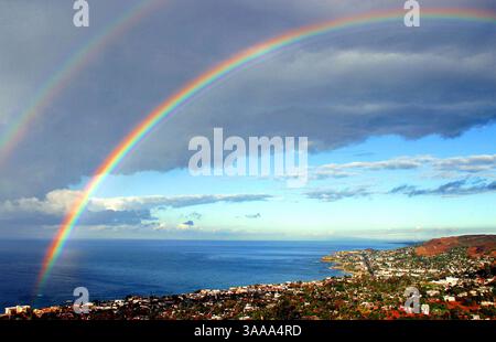 16 giugno 2006; Laguna Beach, CA, Stati Uniti; nella foto è illustrata una panoramica di Laguna Beach, presa da una collina nel sud di Laguna, con uno splendido arcobaleno nel cielo. La Pacific Coast Highway, l'Oceano Pacifico e il fronte oceano di case da milioni di dollari possono essere visti costeggiando le scogliere sopra. Credito obbligatorio: Foto di Geoffrey Ragatz/ZUMA Press. (©) Copyright 2006 di Geoffrey Ragatz Foto Stock