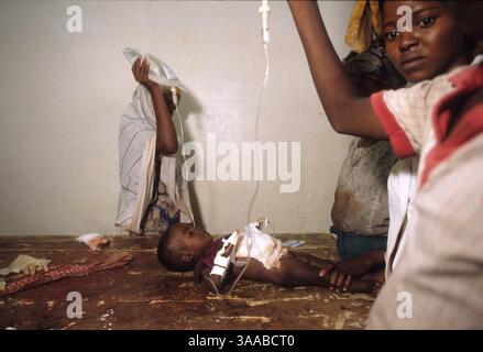 1 agosto 1992; Mogadiscio, SOMALIA; i volontari hanno in mano sacchi IV che danno fluidi a una ragazza di 18 mesi che ha subito una ferita da arma da fuoco quando uomini armati hanno saccheggiato la loro casa. Sua zia l'ha portata in ospedale. Sua madre, suo padre e suo fratello sono stati uccisi nell'attacco. Credito obbligatorio: Foto di Cheryl Hatch/ZUMA Press. (©) Copyright 1992 di Cheryl Hatch Foto Stock