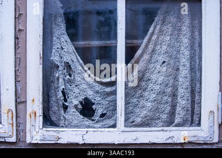 Vecchie tende sporche strappate con fori e finestra rotta. Segni di abbandono domestico. I posti persi hanno distrutto sharm. Casa distrutta. Foto Stock