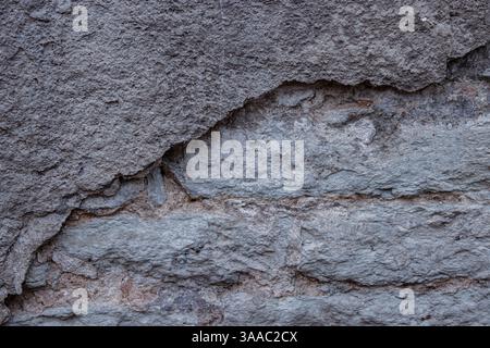 Primo piano di un mattone resistente agli agenti atmosferici, incrinature e patina di un muro di pietra. Trama rustica rustica rustica e dettagli della superficie invecchiata, perfetta per l'uso su sfondo e de Foto Stock