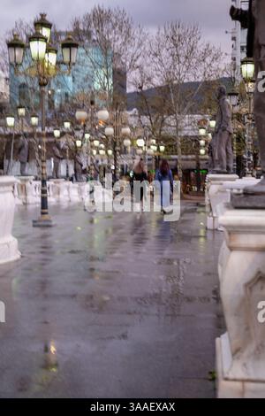 Passeggiata serale piovosa in città. Sfocatura del movimento. Foto Stock