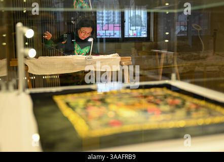 (250401) -- WUHAN, 1 aprile 2025 (Xinhua) -- Ren Wei fa un lavoro di ricamo nel suo studio a Wuhan, nella provincia di Hubei, nella Cina centrale, 14 marzo 2025. Il ricamo Han, un ricamo tradizionale con una storia di oltre 2.000 anni, è stato elencato come uno dei patrimoni culturali immateriali nazionali nel 2008. Famoso per le sue cuciture ruvide, i colori ricchi e i motivi audaci, spesso delinea i motivi del ricamo con linee oro o argento, offrendo un magnifico impatto visivo. Ren Wei, nato in una famiglia di ricami Han, è un erede rappresentativo dell'arte. Da quando aveva 14 anni, Ren lo era Foto Stock