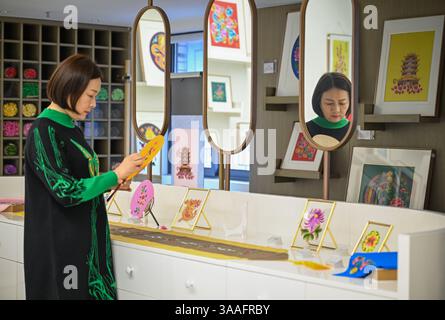 (250401) -- WUHAN, 1 aprile 2025 (Xinhua) -- Ren Wei organizza prodotti culturali e creativi nel suo studio a Wuhan, nella provincia di Hubei, nella Cina centrale, 14 marzo 2025. Il ricamo Han, un ricamo tradizionale con una storia di oltre 2.000 anni, è stato elencato come uno dei patrimoni culturali immateriali nazionali nel 2008. Famoso per le sue cuciture ruvide, i colori ricchi e i motivi audaci, spesso delinea i motivi del ricamo con linee oro o argento, offrendo un magnifico impatto visivo. Ren Wei, nato in una famiglia di ricami Han, è un erede rappresentativo dell'arte. Da quando aveva 14 anni Foto Stock