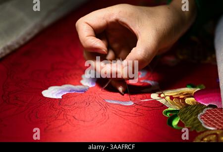 (250401) -- WUHAN, 1 aprile 2025 (Xinhua) -- Ren Wei fa un lavoro di ricamo nel suo studio a Wuhan, nella provincia di Hubei, nella Cina centrale, 14 marzo 2025. Il ricamo Han, un ricamo tradizionale con una storia di oltre 2.000 anni, è stato elencato come uno dei patrimoni culturali immateriali nazionali nel 2008. Famoso per le sue cuciture ruvide, i colori ricchi e i motivi audaci, spesso delinea i motivi del ricamo con linee oro o argento, offrendo un magnifico impatto visivo. Ren Wei, nato in una famiglia di ricami Han, è un erede rappresentativo dell'arte. Da quando aveva 14 anni, Ren lo era Foto Stock