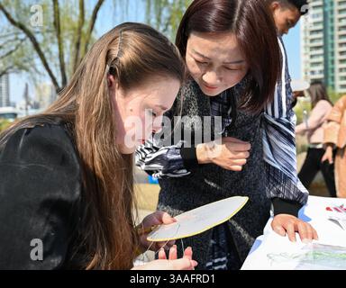 (250401) -- WUHAN, 1 aprile 2025 (Xinhua) -- Ren Wei (R) scambia con un appassionato di ricami Han in un parco vicino al suo studio a Wuhan, nella provincia di Hubei della Cina centrale, 19 marzo 2025. Il ricamo Han, un ricamo tradizionale con una storia di oltre 2.000 anni, è stato elencato come uno dei patrimoni culturali immateriali nazionali nel 2008. Famoso per le sue cuciture ruvide, i colori ricchi e i motivi audaci, spesso delinea i motivi del ricamo con linee oro o argento, offrendo un magnifico impatto visivo. Ren Wei, nato in una famiglia di ricami Han, è un erede rappresentativo dell'arte. Sinc Foto Stock