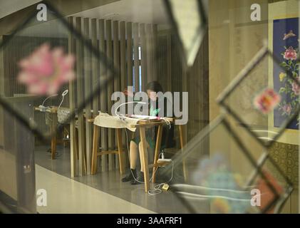 (250401) -- WUHAN, 1 aprile 2025 (Xinhua) -- Ren Wei fa un lavoro di ricamo nel suo studio a Wuhan, nella provincia di Hubei, nella Cina centrale, 14 marzo 2025. Il ricamo Han, un ricamo tradizionale con una storia di oltre 2.000 anni, è stato elencato come uno dei patrimoni culturali immateriali nazionali nel 2008. Famoso per le sue cuciture ruvide, i colori ricchi e i motivi audaci, spesso delinea i motivi del ricamo con linee oro o argento, offrendo un magnifico impatto visivo. Ren Wei, nato in una famiglia di ricami Han, è un erede rappresentativo dell'arte. Da quando aveva 14 anni, Ren lo era Foto Stock