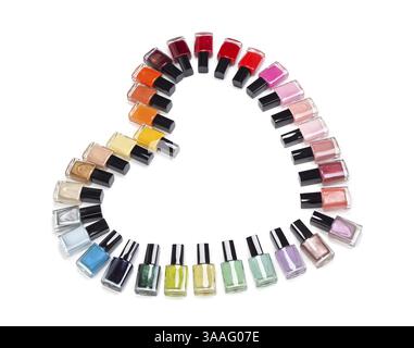Bottiglie multicolori di smalto per unghie a forma di cuore. Isolato su bianco Foto Stock
