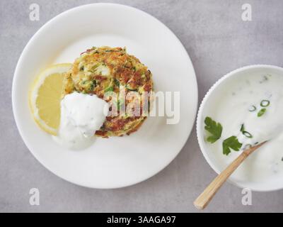 Vista dall'alto di frittelle di verdure croccanti e appetitose sul piatto con yogurt e salsa al limone. Mangiare sano Foto Stock