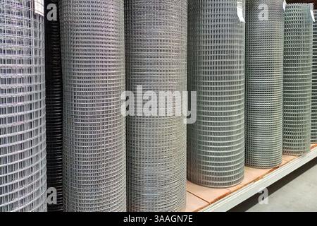 Grandi pile di rotoli industriali a rete metallica disposti ordinatamente su scaffali di stoccaggio in un magazzino, catturando l'essenza dell'ordine e dell'organizzazione per i contro Foto Stock