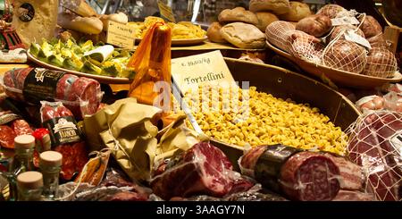 Un'esposizione di cibi freschi italiani, con vari tipi di affettati, pasta (tortellini) e pane. Bologna, Italia. Foto Stock