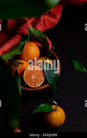 Arance con foglie in una ciotola di legno Foto Stock
