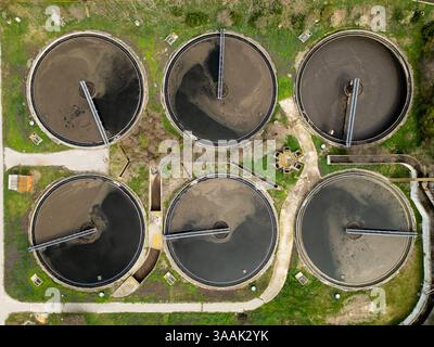 Vista dall'alto dei serbatoi di sedimentazione circolari in un impianto di trattamento delle acque reflue, che mostra il layout geometrico e l'infrastruttura del processo di depurazione dell'acqua Foto Stock