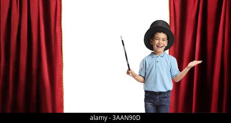 Ragazzo che indossa un cappello da mago e tiene in mano una bacchetta su un palcoscenico teatrale Foto Stock
