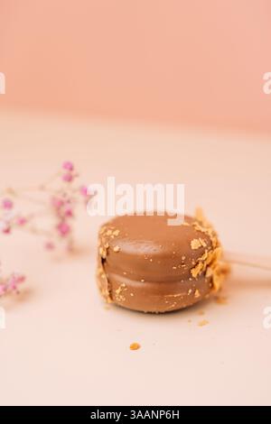 Dessert francesi al cioccolato. Macaron per torte su sfondo rosa, colori pastello, macaroon decorato con noci e cuori diversi, foto verticale. Foto Stock