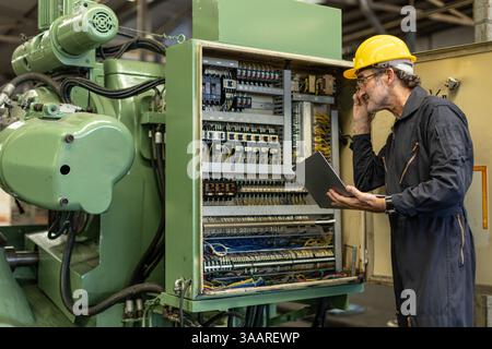 Senior Professional Electrician ingegnere supervisore servizio controllo manutenzione macchina industria pesante cavo elettrico con computer portatile. Foto Stock