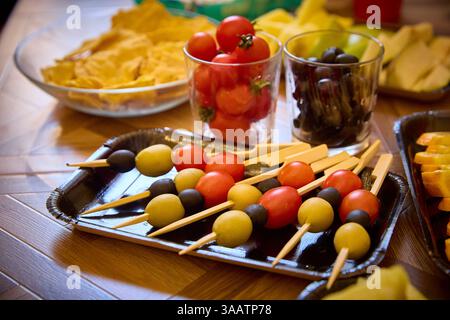 Spiedini di verdure colorati con pomodori ciliegini, olive e altri ingredienti freschi su un tavolo. Perfetto per spuntini da festa o antipasti salutari, Foto Stock