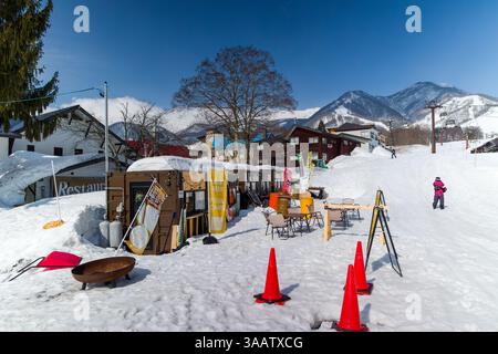 Piccole cabine per cibo e bevande si siedono sulla neve in una giornata di sole alla stazione sciistica di Tsugaike, Nagano, Giappone Foto Stock