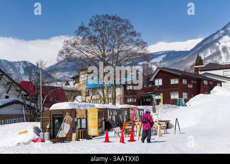 Piccole cabine per cibo e bevande si siedono sulla neve in una giornata di sole alla stazione sciistica di Tsugaike, Nagano, Giappone Foto Stock