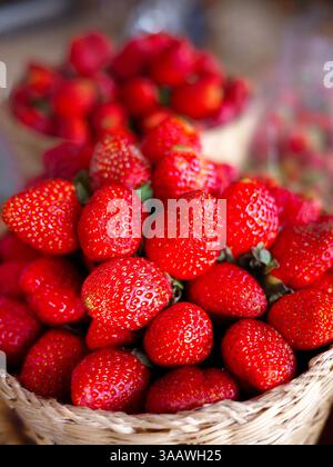 Mazzo di fragole in confezione di cesti di bambù in vendita presso un mercato agricolo, industria della frutta, attività alimentari fresche, mercato dei prodotti biologici conc Foto Stock