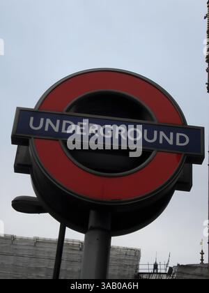 Vista ravvicinata di un cartello della metropolitana di Londra, con l'iconico cerchio rosso e la barra blu con la parola "UNDERGROUND" in lettere bianche. Il backgroun Foto Stock