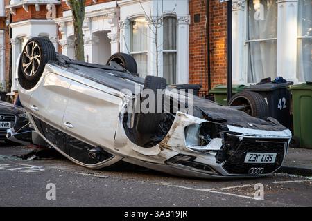 Auto bianca rovesciata "parcheggiata" in una baia per disabili in una strada residenziale di Londra dopo un incidente stradale Foto Stock