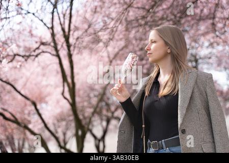 Donna elegante con bicchiere di champagne pieno di fiori nel parco fiorito durante la primavera a Praga Foto Stock