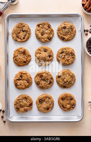 Biscotti con scaglie di cioccolato e noci pecan, biscotti appena sfornati su una teglia da forno rivestita di pergamena Foto Stock