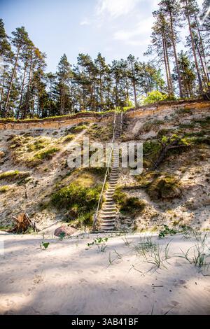 Spiaggia sabbiosa con una ripida costa e scale ripide sul Mar Baltico. Foto Stock