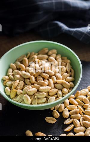 Arachidi salate arrostite in un recipiente su un tavolo di legno. Foto Stock