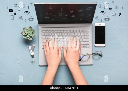 Mani femminili con laptop e telefono cellulare su sfondo grigio. Concetto di marketing digitale Foto Stock