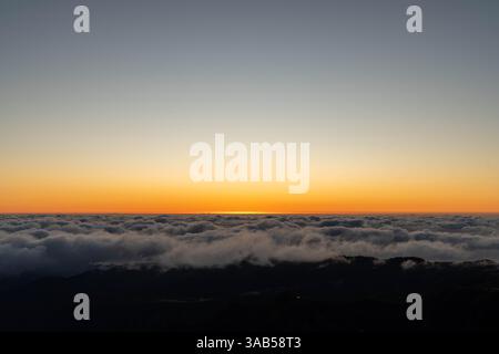 Tramonto dorato sopra le vette e le nuvole delle montagne Foto Stock