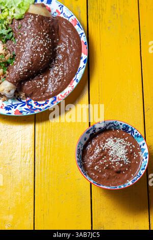Delizioso mole poblano servito con pollo tenero su un vivace tavolo giallo Foto Stock