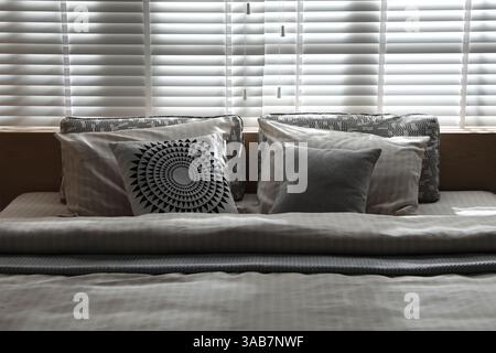 Letto confortevole con lenzuola morbide in camera elegante, primo piano. Design degli interni Foto Stock