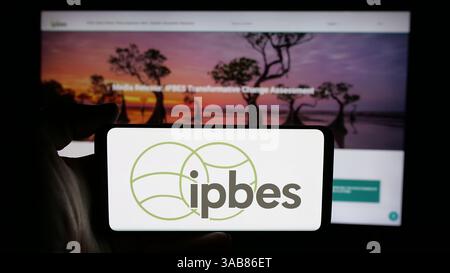 Germania. 7 marzo 2025. In questa immagine, una persona ha in mano un cellulare con il logo dell'organizzazione intergovernativa IPBES sullo schermo davanti alla pagina Web. (Foto di Timon Schneider/SOPA Images/Sipa USA) *** esclusivamente per notizie editoriali **** credito: SIPA USA/Alamy Live News Foto Stock