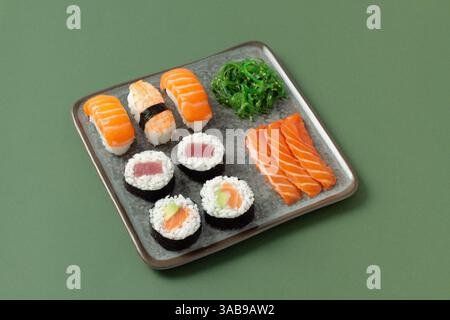 Deliziosa tavola con una varietà di sushi con nigiri, maki, sashimi e insalata di alghe. Immagine perfetta per la cucina giapponese e il cibo fresco Foto Stock
