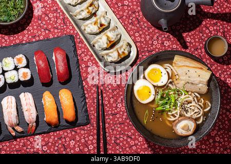Vista dall'alto verso il basso di un'elegante cena di sushi con una varietà di piatti giapponesi, girata in studio con luce dura per migliorare texture e dettagli Foto Stock