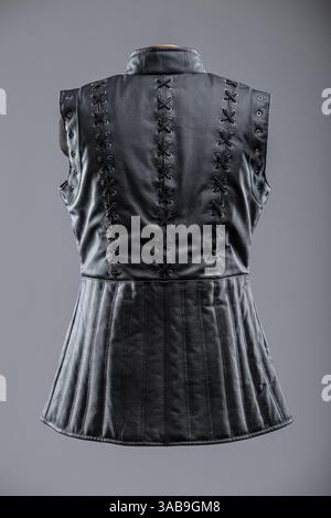 Giacca senza maniche in pelle nera con allacciatura e fibbie. Questa immagine mostra una giacca o un gilet senza maniche in pelle nera con collo alto. È dotato di de Foto Stock