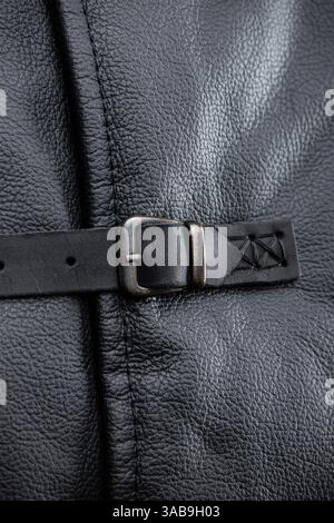 Primo piano della fibbia in pelle. Questa immagine mostra un primo piano di una fibbia argentata su un cinturino in pelle nero, che fa parte della giacca senza maniche. TH Foto Stock