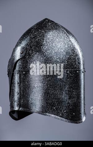 Elmetto da cavaliere medievale chiuso con piccole perforazioni. Questa immagine mostra un casco da cavaliere medievale chiuso, probabilmente in acciaio, con una parte superiore appuntita Foto Stock
