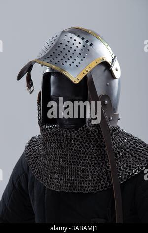 Armadietto in acciaio con visiera aperta. Casco medievale con dettagli in ottone e protezione per la posta in catena. Foto Stock