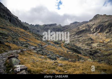 Gli escursionisti camminano lungo un sentiero di montagna in pietra che si snoda attraverso l'aspro paesaggio dei Monti Gredos in Spagna Foto Stock