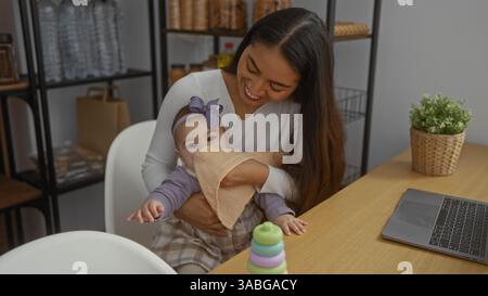 La madre pulisce amorevolmente la bocca del bambino in un accogliente soggiorno, mostrando calore e cura con la figlia nelle vicinanze, circondati da elementi casalinghi, creando Foto Stock