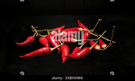 Peperoncini rossi in una composizione dallo stile minimalista scuro Foto Stock