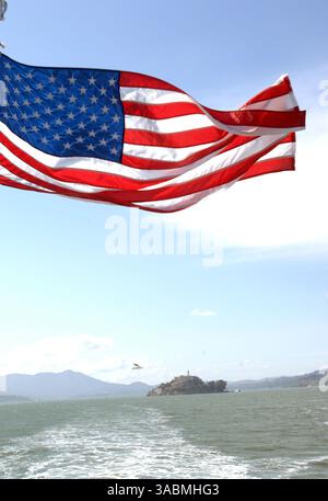 30 novembre 2007 - San Francisco, California, Stati Uniti - una bandiera americana, Old Glory, Stars and Stripes vola dal retro del traghetto con Alcatraz Island sullo sfondo. Alcatraz Island è una piccola isola situata nel mezzo della baia di San Francisco. Servì come faro, poi come fortificazione militare, poi come prigione militare seguita da una prigione federale fino al 1963, quando divenne un'area ricreativa nazionale. Oggi, l'isola è un sito storico supervisionato dal National Park Service come parte dell'area ricreativa nazionale Golden Gate ed è aperta ai tour. I visitatori possono raggiungere l'isola in traghetto Foto Stock