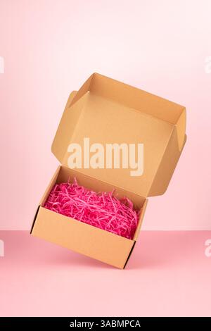 Mockup con scatola di cartone su sfondo rosa. Concetto pubblicitario minimo. Foto Stock
