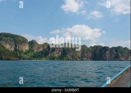Passando davanti alle rigogliose scogliere di Krabi sotto un cielo pieno di morbide nuvole Foto Stock